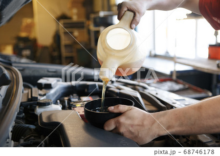 Pouring oil to car engine, Pouring oil to car engine, 68746178