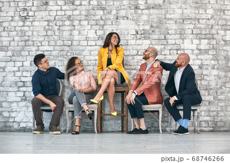 Beautiful cheerful professional woman wearing eyeglasses seated with male co-workers and team leader at work Beautiful cheerful professional woman wearing eyeglasses seated with male co-workers and team leader at work 68746266