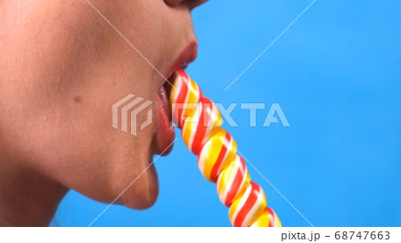 sexy brunette woman with lollipop isolated on a blue background. 68747663