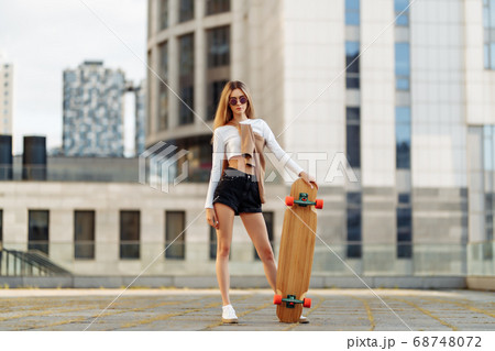Growth portrait of a woman and a longboard. 68748072