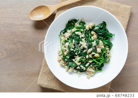 top view of stir fried ivy gourd with egg in a ceramic dish on wooden table. top view of stir fried ivy gourd with egg in a ceramic dish on wooden table. 68748233