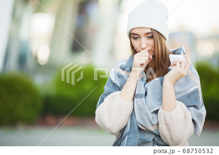 Woman with flu outdoors dressed in cap Woman with flu outdoors dressed in cap 68750532