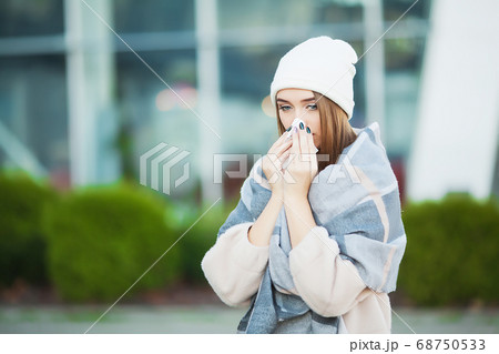 Young woman blowing her nose on the park. Young woman blowing her nose on the park. 68750533