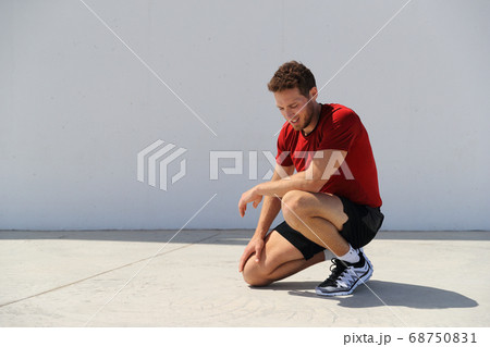 Tired sport fitness man exhausted breathing after difficult workout outdoors. Heat exhaustion athlete dehydrated or runner with knee injury pain resting in disappointment 68750831