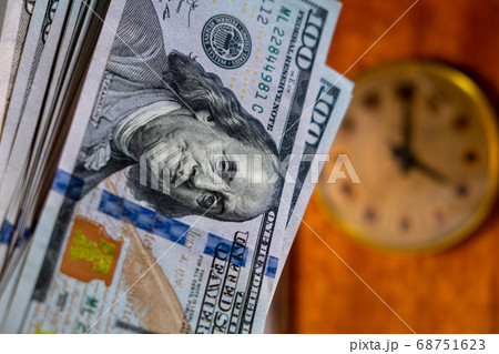 close up of many US dollar banknotes with vintage clock on background. time is money concept 68751623