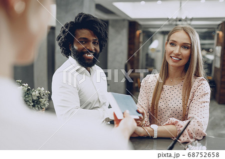 Business trip concept. Black man and caucasian woman businesspeople colleagues checking-in in hotel 68752658