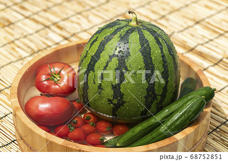 桶で冷やすスイカと夏野菜の写真素材