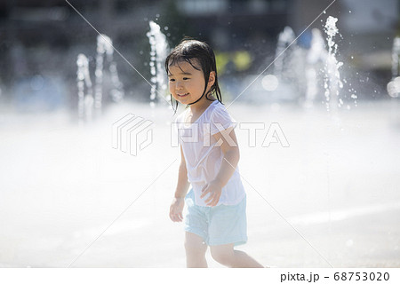 広場の噴水で水遊びする子供の写真素材