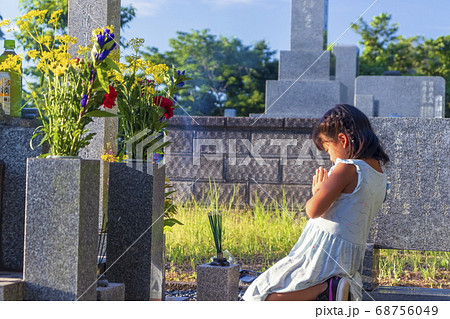 お墓参り　墓前で手を合わせて黙とうする女の子 68756049
