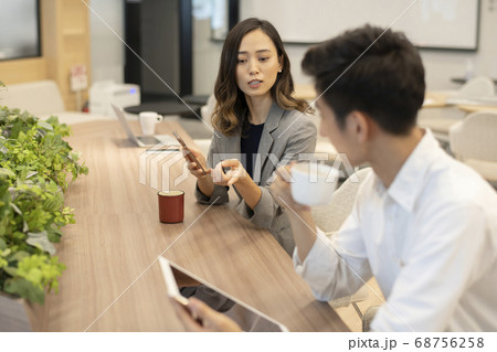 カウンターに座りタブレットで調べたことについて会話をする男子と女性 68756258