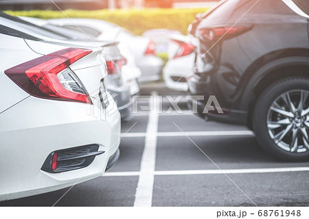 Car parking in large asphalt parking lot with trees 68761948