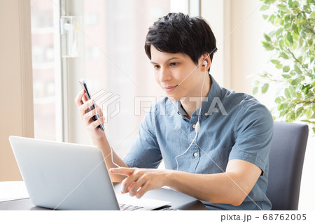 仕事中にスマホでイヤホン通話する男性 68762005