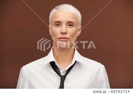 Serious mature blond businesswoman in white shirt and black tie looking at you 68762724