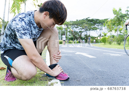 Asian man use hands hold on his ankle while 68763738