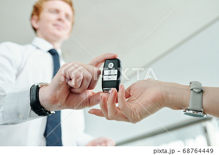 Hand of young woman taking remote control alarm system of her new car Hand of young woman taking remote control alarm system of her new car 68764449