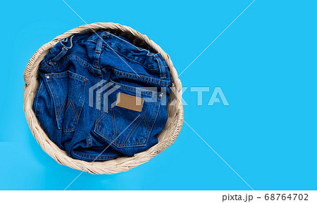 Jeans in laundry basket on blue background. Jeans in laundry basket on blue background. 68764702