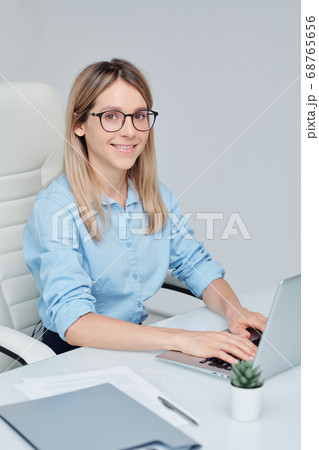 Young successful businesswoman in eyeglasses looking at you with toothy smile 68765656