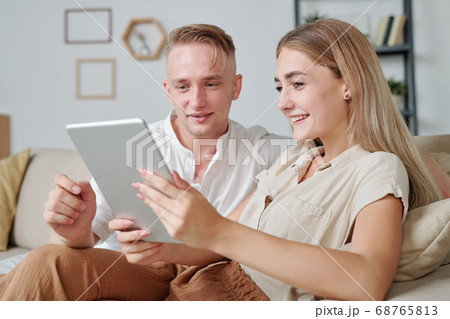 Contemporary young affectionate couple using tablet to watch online video 68765813