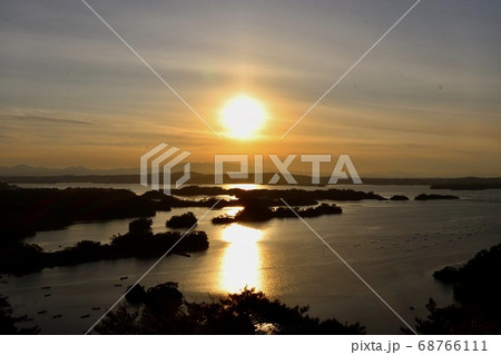 沈む太陽に照らされる島々と海に伸びる光の写真素材