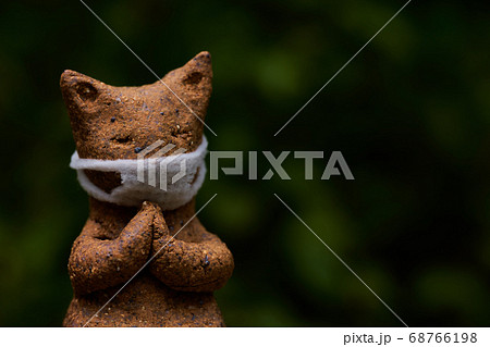 マスクをした陶器の拝み猫です の写真素材