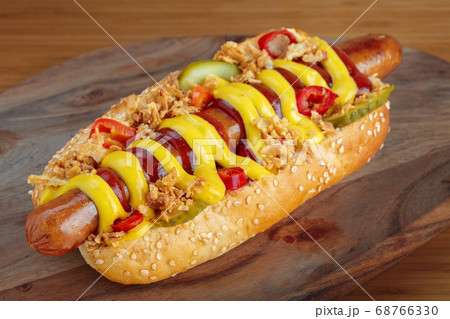 Hot dog with yellow mustard and ketchup on wooden board Hot dog with yellow mustard and ketchup on wooden board 68766330