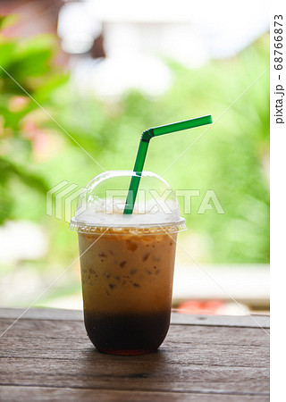 Iced coffee latte in plastic cup on wooden table 68766873
