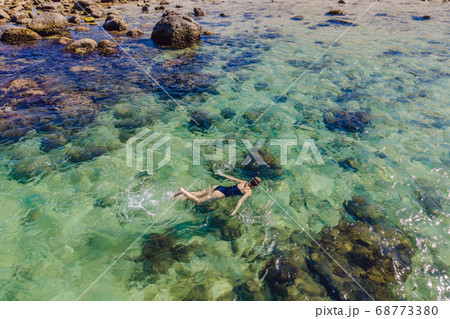 The woman is snorkeling among the corals. View from the drone 68773380