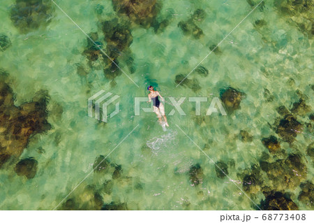 The woman is snorkeling among the corals. View from the drone 68773408