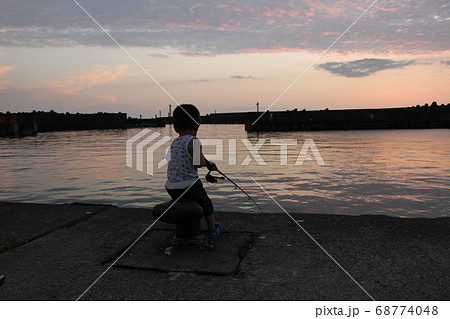 夕暮れの港で堤防釣りをする男の子 幼児 の写真素材