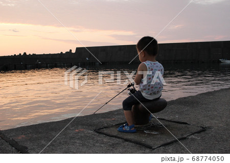 夕暮れの港で堤防釣りをする男の子 幼児 の写真素材