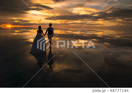 天空の鏡の夕陽に向かう花嫁と花婿 68777184
