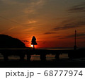 沈む夕陽を見つめる女性 68777974