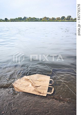 Discarded shopping paper bag in water. Discarded shopping paper bag in water. 68778376