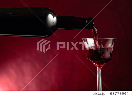 Red wine is poured from an old bottle into a Red wine is poured from an old bottle into a 68778944