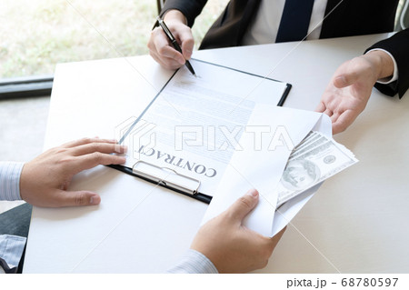 Businessman giving bribe money in the envelope of 68780597