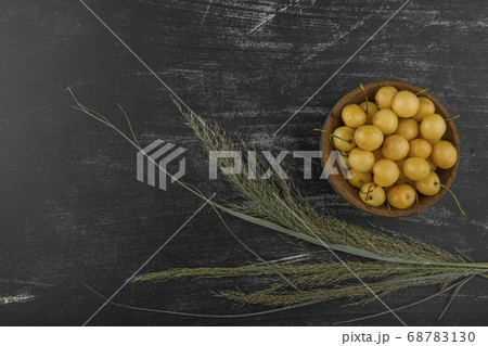 Yellow cherries in a wooden bowl in the right side with herbs Yellow cherries in a wooden bowl in the right side with herbs 68783130