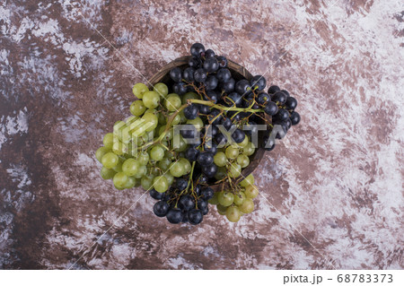 A bunch of green and red grapes in the middle on the marble A bunch of green and red grapes in the middle on the marble 68783373