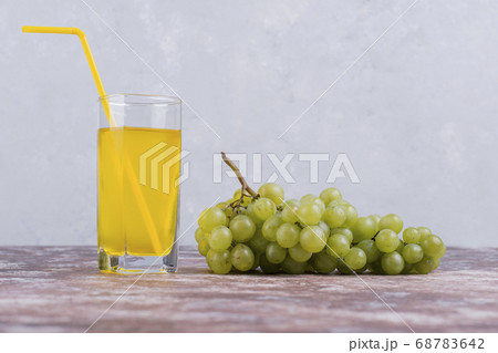 A bunch of green grapes with a glass of juice on blue background A bunch of green grapes with a glass of juice on blue background 68783642