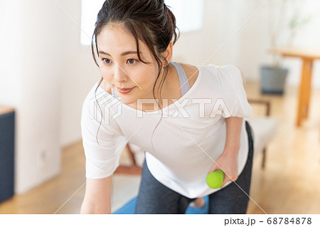 部屋でダンベルで筋トレする若い女性 68784878