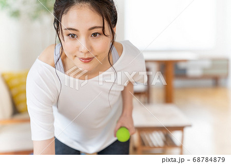 部屋でダンベルで筋トレする若い女性 部屋でダンベルで筋トレする若い女性 68784879