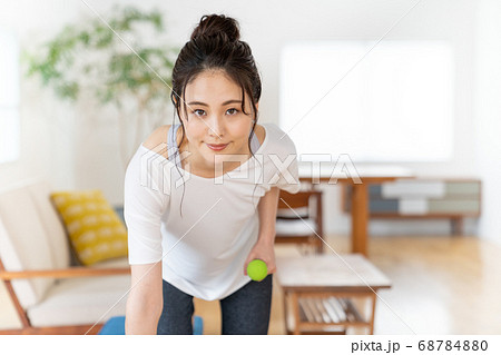 部屋でダンベルで筋トレする若い女性 部屋でダンベルで筋トレする若い女性 68784880