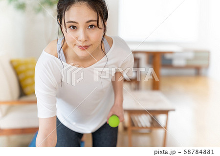 部屋でダンベルで筋トレする若い女性 部屋でダンベルで筋トレする若い女性 68784881