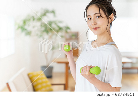 部屋でダンベルで筋トレする若い女性 部屋でダンベルで筋トレする若い女性 68784911