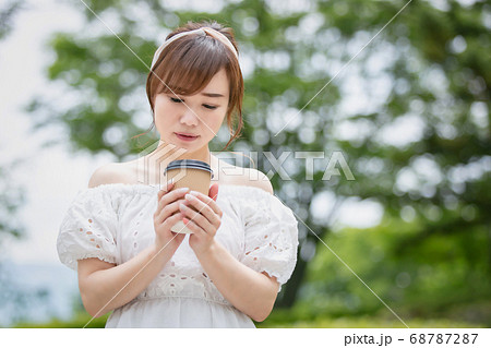 公園でホットドリンクを飲むアジア人女性（困る） 68787287