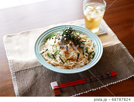 テーブルに置かれた、夏にぴったりの冷たいおろし納豆うどんと麦茶 68787824