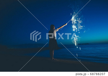 夜の海で花火をする女性の写真素材