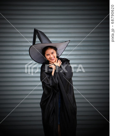 Woman with black cape and witch hat use her hands to strangle her neck 68790620