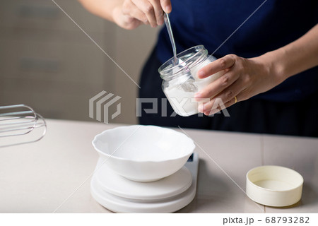 Woman measuring sugar on a small kitchen scale Woman measuring sugar on a small kitchen scale 68793282