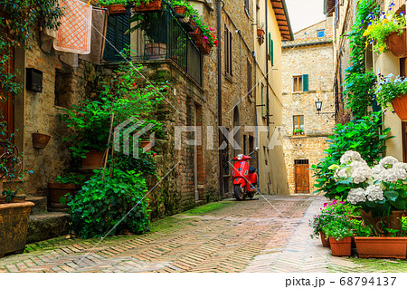 Typical Italian street with colorful flowers and scooter, Pienza, Tuscany 68794137