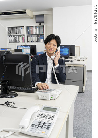 会社のディスクで仕事中電話をする若い男性 会社のディスクで仕事中電話をする若い男性 68796251